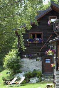 a log cabin with two lawn chairs in front of it at "CHALET dei FIORI" room & apartment in Bedretto