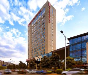 un edificio alto con coches en una calle de la ciudad en Hilton Garden Inn Xi'an High-Tech Zone en Xi'an