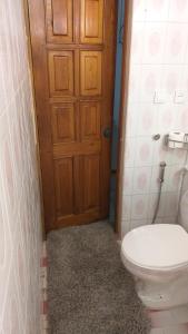ein Badezimmer mit einem WC und einer Holztür in der Unterkunft poti apartment in Poti