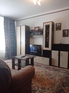 een woonkamer met een bank, een tafel en een tv bij Modern Beach Apartment in Constanţa