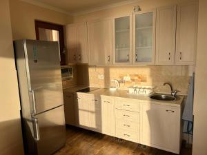 een keuken met witte kasten en een roestvrijstalen koelkast bij Apartment Sea View Dobra Voda in Dobra Voda