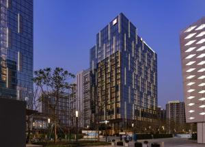 Hilton Garden Inn Shenzhen World Exhibition & Convention Center في شنجن: مبنى زجاجي طويل في مدينة في الليل