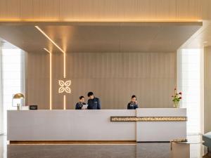 three men standing at a reception desk in a lobby at Hilton Garden Inn Shenzhen World Exhibition & Convention Center in Shenzhen