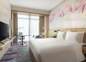 um quarto de hotel com uma grande cama branca e uma secretária em Hilton Garden Inn Shenzhen World Exhibition & Convention Center em Shenzhen