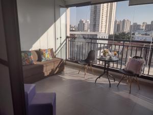 a living room with a couch and a table on a balcony at Lindo Studio no bom Retiro prox ao anhembi Sambodromo com wifi in São Paulo
