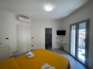 - une chambre avec un lit jaune et une grande fenêtre dans l'établissement Domu Dina Affittacamere 1, à Tertenìa