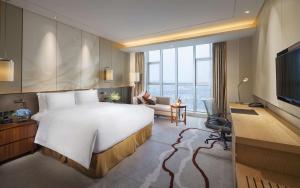 Cette chambre comprend un grand lit et une télévision. dans l'établissement DoubleTree by Hilton Hotel Qingdao-Jimo Ancient City, à Jimo