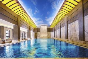 een groot zwembad in een gebouw met een plafond bij Hilton Tianjin Eco-City in Binhai