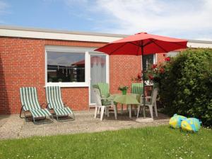 a patio with a table and chairs and an umbrella at Bungalow, Dornumersiel in Dornumersiel