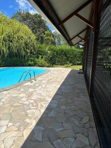 a swimming pool with a stone walkway next to a house at Villa REYDISIA in Saint-Laurent du Maroni