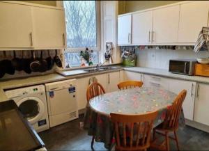 Cosy loft room in Morningside, Edinburgh في إدنبرة: مطبخ مع طاولة وكراسي وغسالة ملابس