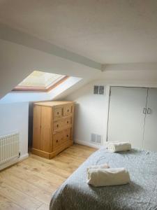 1 dormitorio con cama y tocador de madera en Cosy loft room in Morningside, Edinburgh en Edimburgo