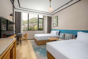 MaotaiにあるHilton Garden Inn Guizhou Maotai Townのベッド2台とデスクが備わるホテルルームです。