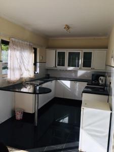 a kitchen with white cabinets and a black counter top at Platinum Villa Guest House in Nhlangano +7 photos