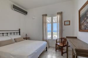 a bedroom with a bed and a desk and a window at Big Blue Sunset View in Angairiá