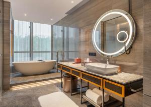 a bathroom with a tub and a sink and a mirror at Canopy by Hilton Xi'an Qujiang in Xi'an