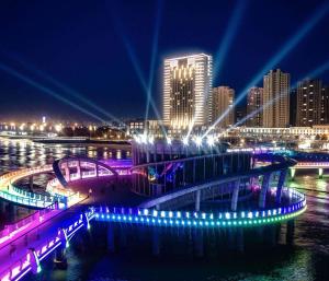 een brug over een rivier met een stad in de nacht bij Hilton Yantai Golden Coast in Yantai