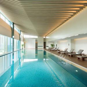 a swimming pool in a building with chairs and a ceiling at Hilton Yantai Golden Coast in Yantai