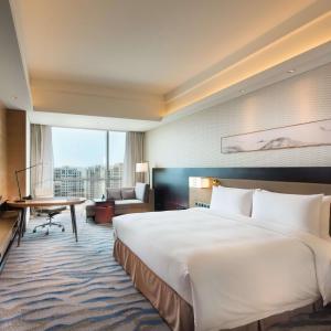 a hotel room with a large bed and a desk at Hilton Yantai Golden Coast in Yantai