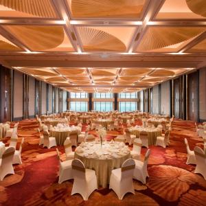 a large banquet hall with tables and white chairs at Hilton Yantai Golden Coast in Yantai