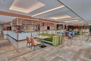 a restaurant with tables and chairs and a kitchen at Hilton Yancheng in Yancheng