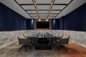 a conference room with a large table and a screen at Hilton Yancheng in Yancheng