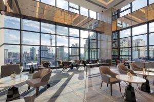 a lobby with tables and chairs and large windows at Doubletree By Hilton Yangzhou in Yangzhou