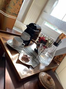 Elena Kempf Haaratelier & Guesthouse في برونفلس: طاولة عليها صانع قهوة و كاسات
