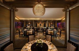 una sala da pranzo con tavoli, sedie e lampadario a braccio di Hilton Haikou Meilan a Haikou