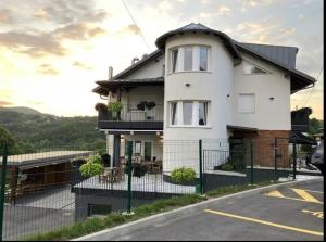 a white house with a fence on a street at Guesthouse Frlan in Ozalj