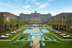 a resort with a pool and chairs and a large building at Hilton Haikou Meilan in Haikou
