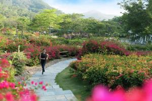 a woman walking down a path through a flower garden at Joyze Hotel Xiamen, Curio Collection By Hilton in Xiamen