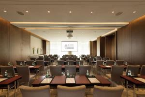 a conference room with tables and chairs and a screen at Joyze Hotel Xiamen, Curio Collection By Hilton in Xiamen