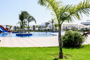 a swimming pool with a slide and a palm tree at Luxury Four seasons Life Ruby Apartment Bogaz in Boğaz