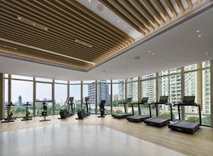a gym with cardio equipment in a building with windows at Hilton Foshan Shunde - Free Canton Fair Shuttle Bus in Shunde
