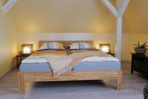 ブラウンフェルスにあるElena Kempf Haaratelier & Guesthouseのベッドルーム1室(木製ベッド1台、ランプ2つ付)