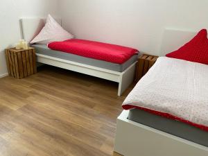 sypialnia z 2 łóżkami z czerwonymi poduszkami i drewnianą podłogą w obiekcie Ferienwohnung am Liederbach w mieście Waldshut-Tiengen