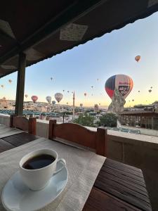 a cup of coffee sitting on a table with hot air balloons at Goreme House in Göreme