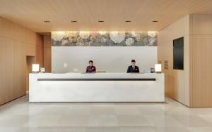 two people sitting at a reception desk in a lobby at DoubleTree by Hilton Taipei Zhongshan in Taipei