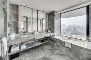 a bathroom with two sinks and a tub and a window at DoubleTree by Hilton Taipei Zhongshan in Taipei