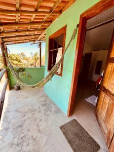 a house with a hammock hanging from the side of it at Pousada Clara in Caraíva