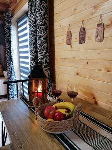 a basket of fruit on a table with two glasses of wine at Agroturystykadomkistawisko in Solina