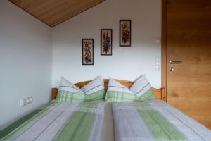 Schlafzimmer mit einem Bett mit grünen und weißen Kissen in der Unterkunft Ferienhaus Bergblick Bregenzerwald in Bregenz