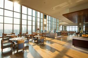 a restaurant with tables and chairs and large windows at Hilton Shijiazhuang in Shijiazhuang