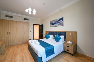 a bedroom with a large bed with blue pillows at Saray Musheireb Hotel Suites and Apartment in Doha