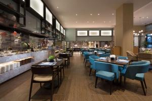 a restaurant with tables and blue chairs and a counter at Doubletree By Hilton Qingdao Oriental Movie Metropolis in Huangdao