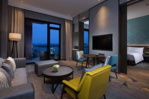 a hotel room with a bed and a living room at Doubletree By Hilton Qingdao Oriental Movie Metropolis in Huangdao