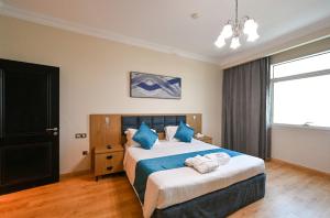 a bedroom with a large bed with blue pillows at Saray Musheireb Hotel Suites and Apartment in Doha