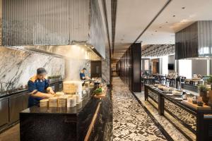 a kitchen with two people preparing food in a restaurant at Conrad Hangzhou Tonglu in Yinzhu