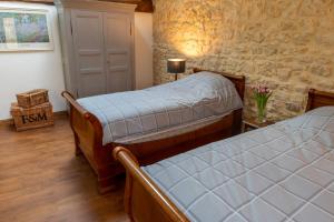 1 dormitorio con 2 camas y pared de piedra en Moulin du Fontcourt, en Chasseneuil-sur-Bonnieure